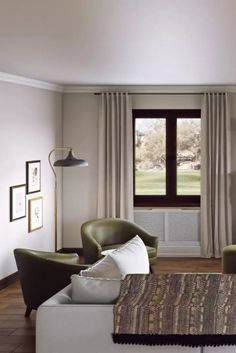 a living room with two green chairs and a coffee table in front of a window