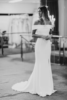 a woman in a white dress is posing for a black and white photo with her hand on her hip