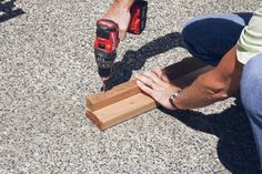 a person using a drill to attach a piece of wood on the ground with a cordless screwdriver