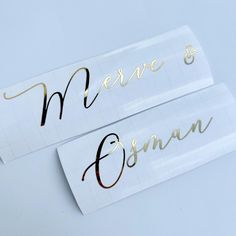 two white stickers with gold lettering that say merrie and susan on them, sitting next to each other