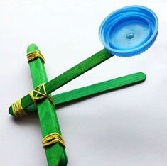 three green sticks tied to each other with a blue plastic cup in the middle one