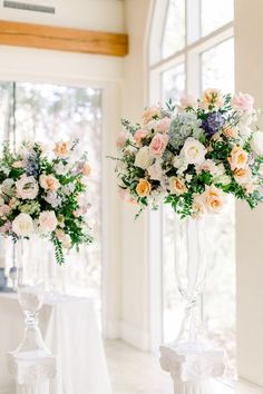 two tall vases filled with flowers sitting next to each other on top of a table