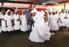 a man standing in front of a group of people wearing white dresses and head coverings