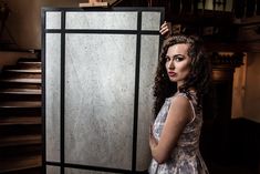 a woman is standing in front of a door with her hand on the top of it