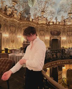 a man standing in front of a chandelier with his hands on the chair