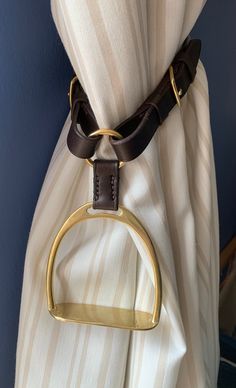 a curtain with a gold ring hanging from it's side and a white drapes behind it