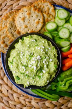 a plate with crackers, cucumber, carrots and celery