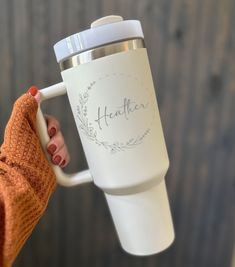 a woman holding a white coffee cup with the word health written on it and her arm wrapped in an orange mitt