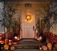 a front door decorated for halloween with pumpkins and candles