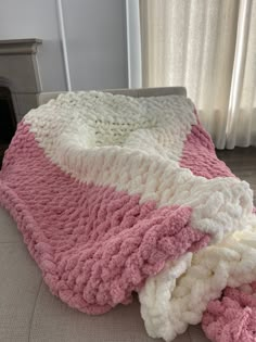 a pink and white blanket is laying on the floor