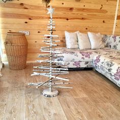 a christmas tree made out of branches in the middle of a living room with couches