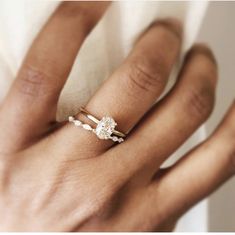 a woman's hand with a diamond ring on top of her finger and the other hand holding it