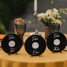 three black clocks sitting on top of a table next to a vase filled with flowers