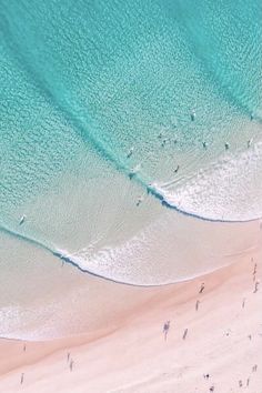 an aerial view of people walking on the beach and in the water, from above