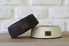 two black and white dog bowls sitting on top of a wooden table next to a brick wall