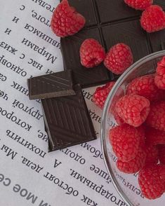 some raspberries and chocolate are sitting on a piece of paper next to it