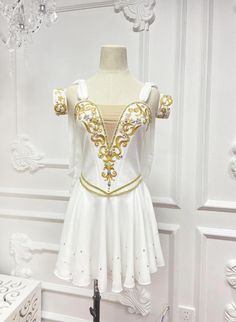 a white and gold dress on display in front of a wall with chandelier