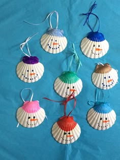 six seashells with snowmen painted on them are hanging from strings and tied together