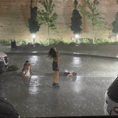 two women are standing in the middle of an empty parking lot with cars parked nearby