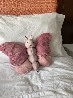 a pink butterfly stuffed animal laying on top of a bed