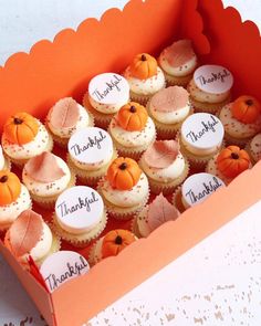 a box filled with lots of cupcakes covered in frosting and decorated like pumpkins