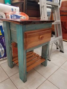 a wooden table sitting on top of a tile floor next to a ladder and other items