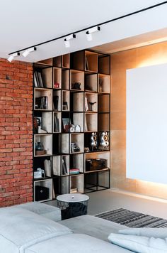 a living room filled with furniture and bookshelves next to a brick wall in front of a window