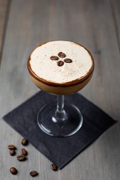 a drink in a glass with coffee beans on the side