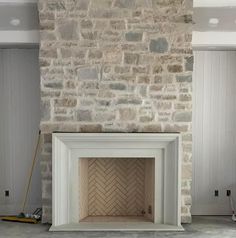 an empty fireplace in a room with white walls and gray brickwork on the wall