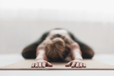 a woman is laying down on a yoga mat with her hands behind her head and feet in the air