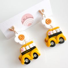 two yellow school bus shaped earrings are next to a card