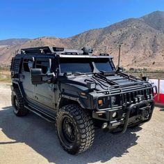 an armored vehicle parked in the desert with mountains in the background