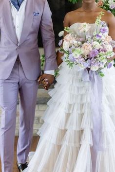 a bride and groom are walking down the aisle holding hands with each other as they hold their bouquets