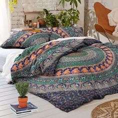 a bed with blue and green bedspread next to a potted plant