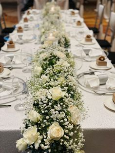 a long table with white flowers and place settings