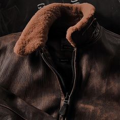 a leather jacket with a fur collar and zippers on the front, sitting against a black background