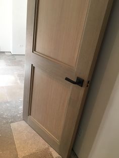 an open wooden door in the middle of a room with tile flooring and white walls