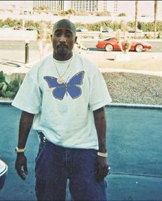 a man standing in front of a car with a butterfly on his shirt