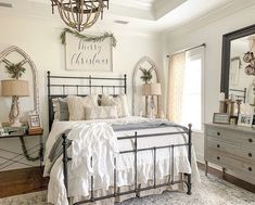 a bedroom decorated for christmas with white bedding and decorations on the headboard, dresser and mirror