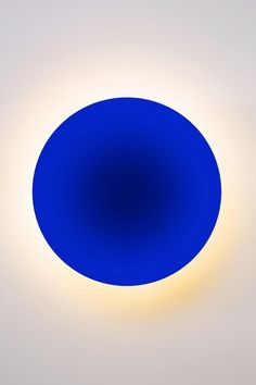 a blue circular object is shown in the middle of a white wall with light coming from it