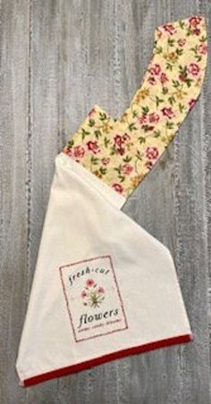 two flowered tea towels on top of each other, one has a red border and the other is white