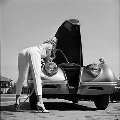 a woman leaning on the hood of a car