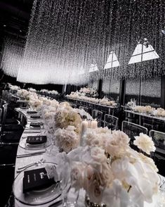 a long table is set with white flowers and candles for an elegant wedding reception in black and white