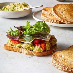 there is a sandwich with lettuce, tomatoes and other foods on the table