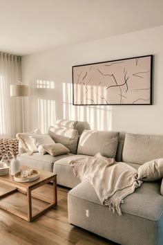 a living room filled with furniture and a large painting on the wall above it's windows