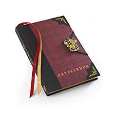 a harry potter notebook with a hogwarts pin on the front and red cover