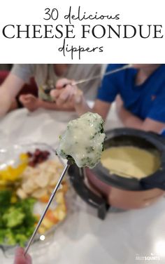 a person holding a skewer with cheese on it in front of a plate of food