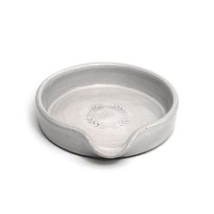 a small white bowl with a flower design on the side and a circular base in the middle