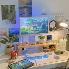 a desk with a computer monitor, keyboard and phone on it next to a plant