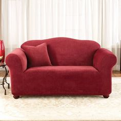 a red couch sitting on top of a white rug